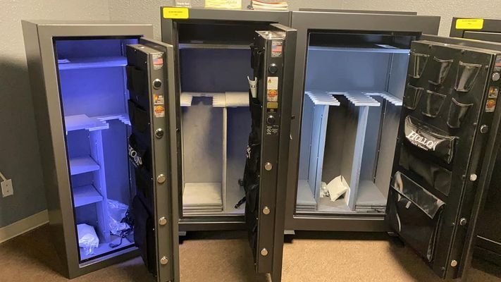 Open gun safes with interior shelving and door organizers. Gray and black metal.