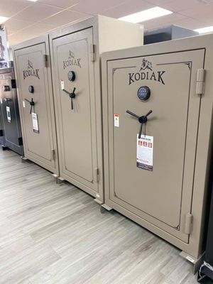 Three beige Kodiak gun safes lined up in a store, with electronic keypads and black handles.