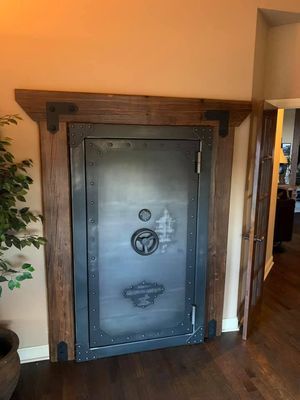 A heavy-duty steel vault door set in a wooden frame. Dark metal door with bolted design, framed in brown wood.