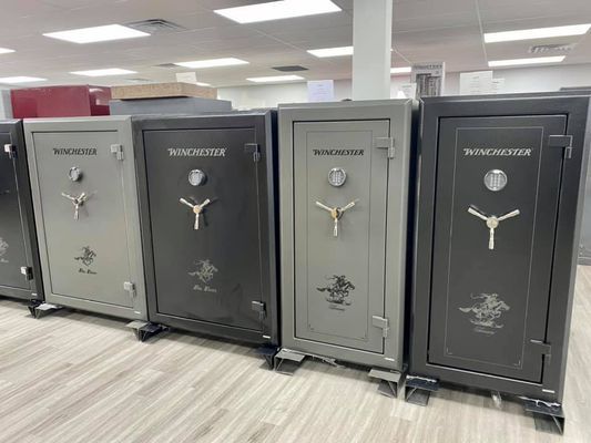 Row of gray and black Winchester gun safes in a showroom, each with a combination lock and handle.
