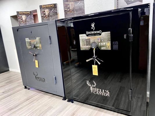 Two large, black and gray gun safes with logos in a showroom.