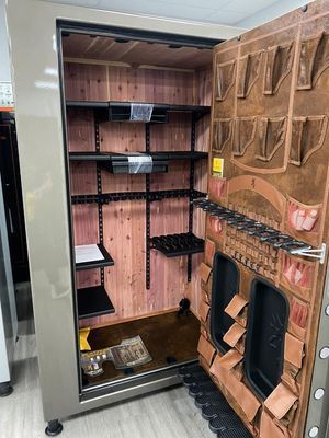 Open gun safe with wooden interior, shelves, and racks. Brown and beige tones.