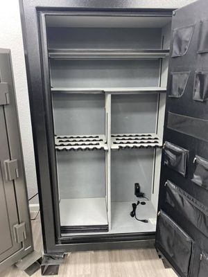 An open black gun safe with gray shelves and gun racks. The door has storage pockets.