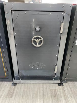 Dark gray safe with dial, handle, and bolted frame on a gray floor.