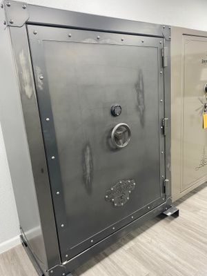 Dark gray steel safe with a round handle, digital lock, and riveted frame.