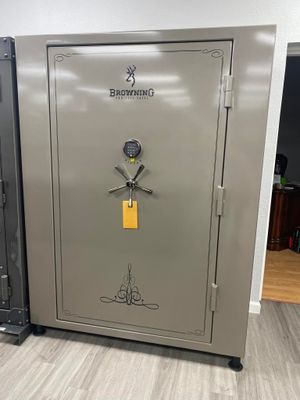 A large, tan Browning gun safe with a combination lock, open door, and decorative accents, on a light wood floor.