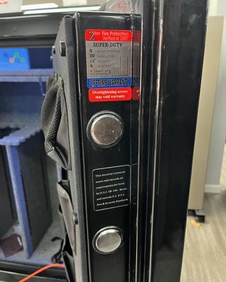 Black gun safe door with fire protection label, door handle, and inside compartment visible.