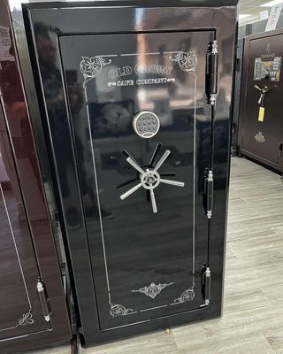 Black security safe with silver handle and decorative details, standing in a store.