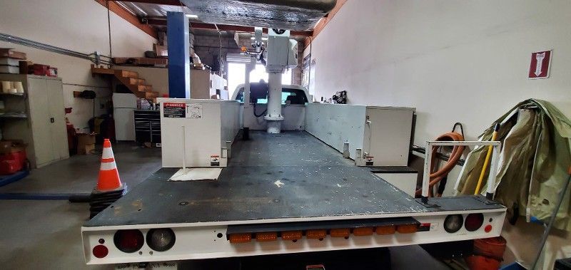 A large flatbed truck is parked in a garage.