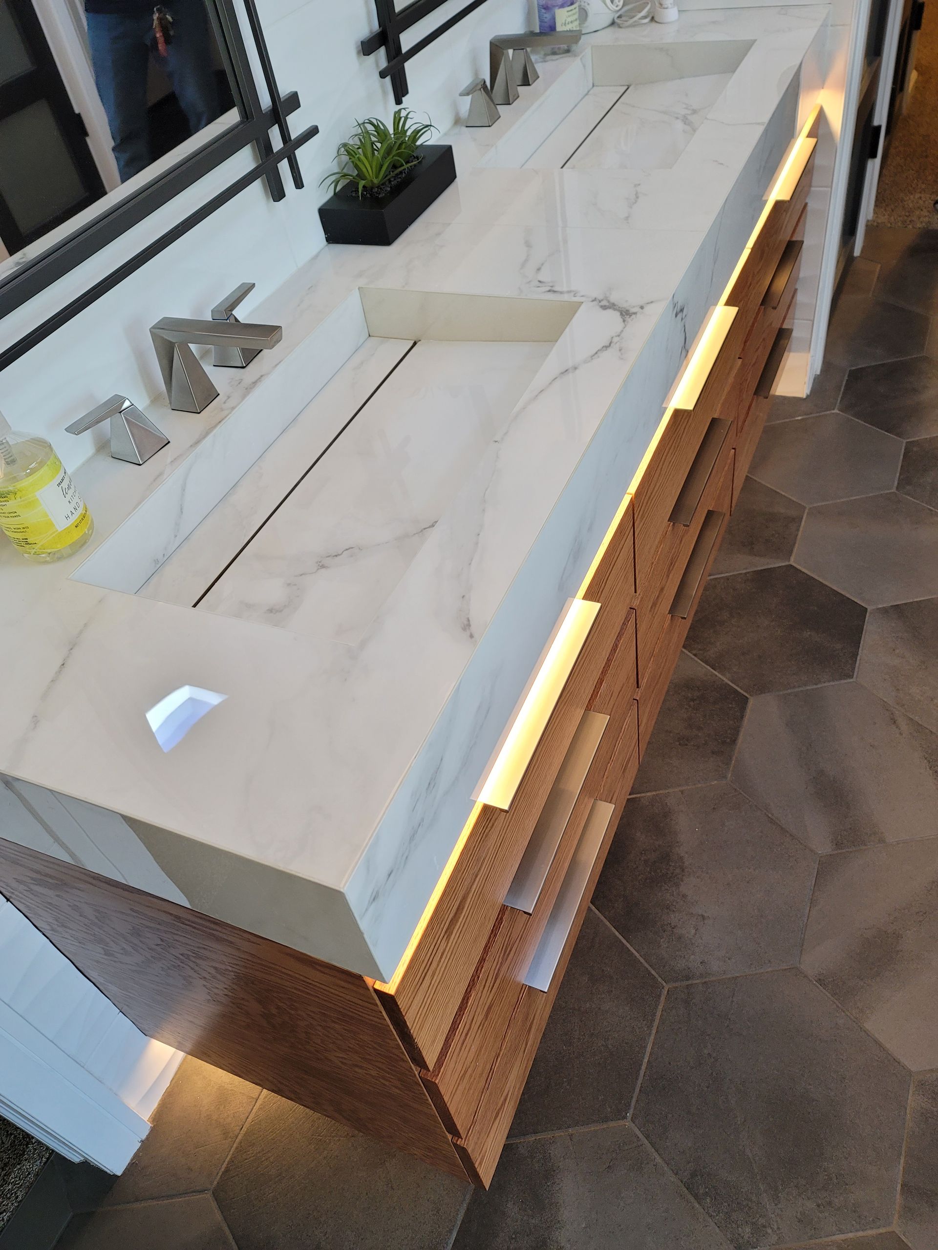 Modern kitchen island with white marble countertop, wood base, sink, and warm under-cabinet lighting