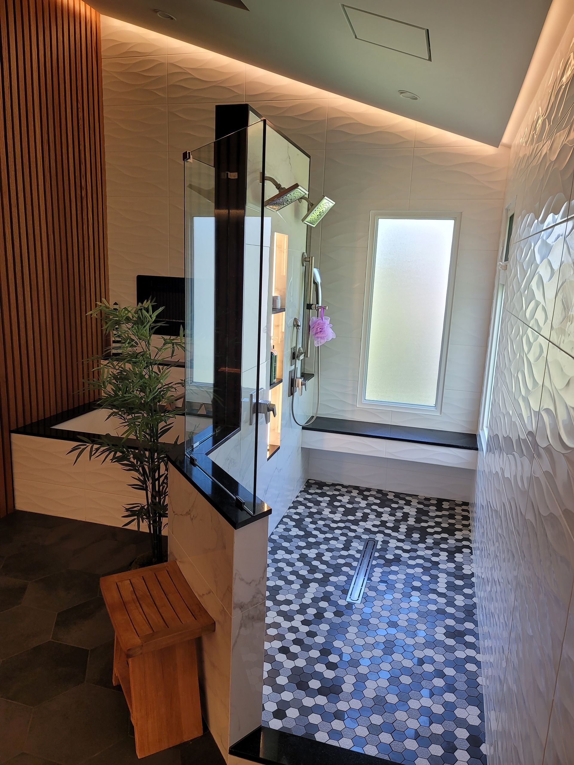 Modern spa-like interior with patterned tile floor, wall mirror, and wooden bench