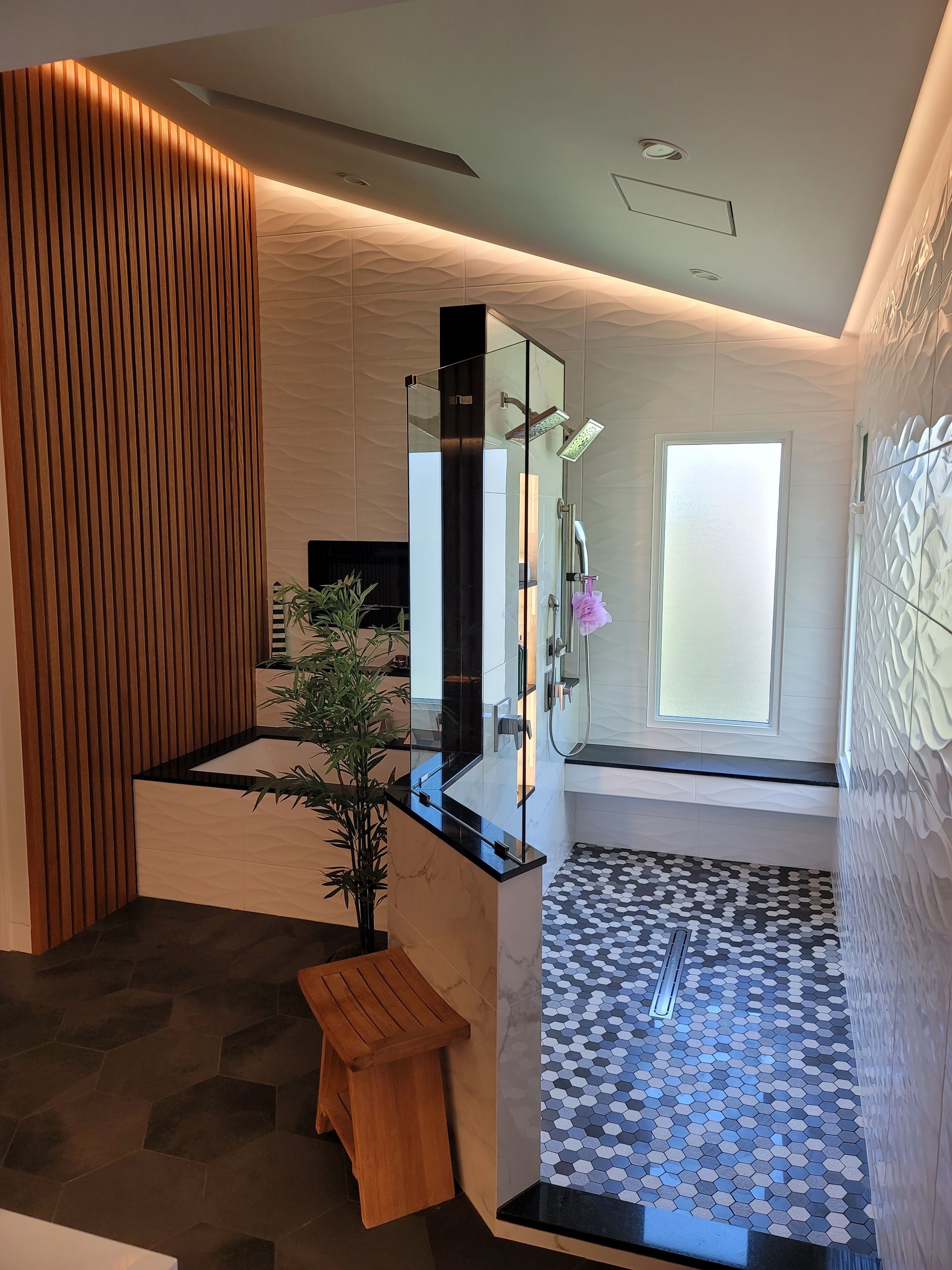 Modern hallway with warm lighting, mirror, bench, potted plant, and patterned tile floor.