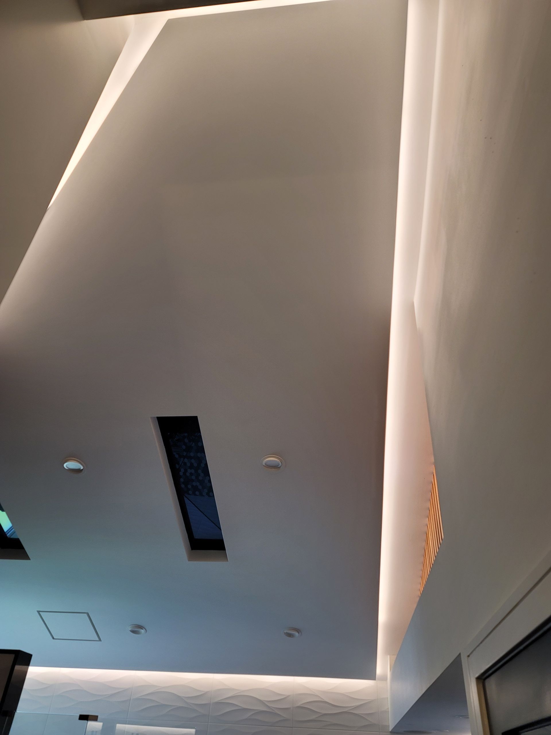 Modern interior ceiling with recessed lights, skylight, and tall wall panels