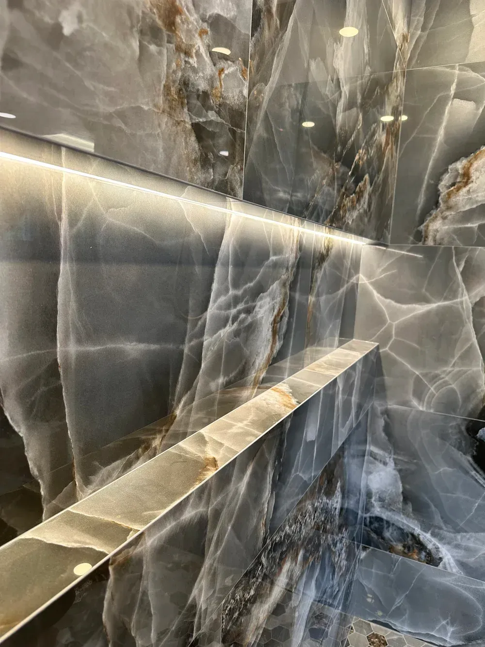 Polished dark marble wall with white veining and a gold-toned ledge in a modern interior