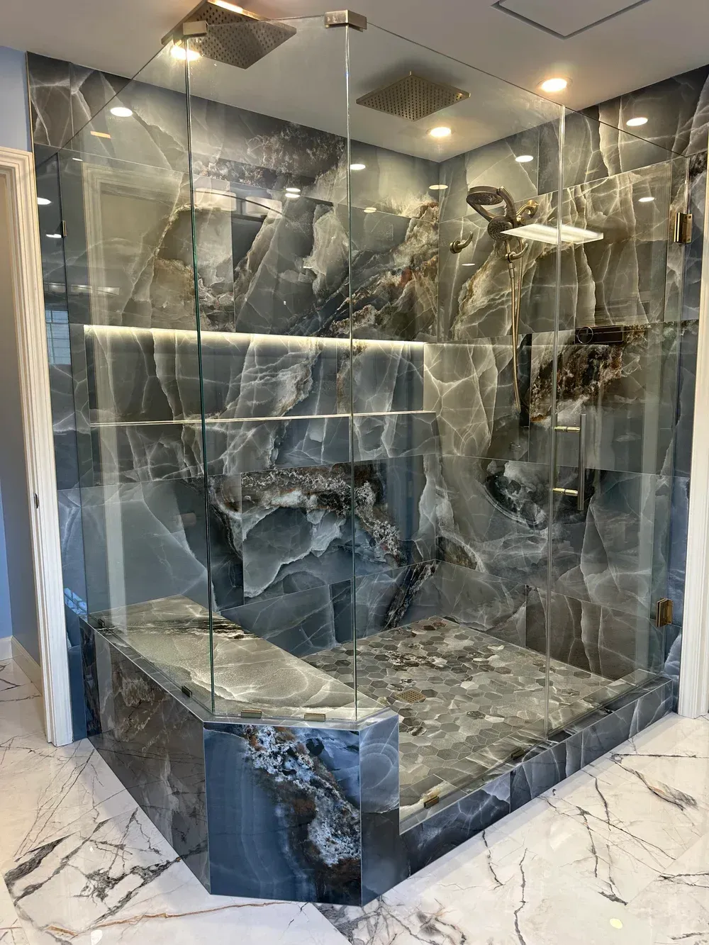 Marble-clad glass display case with stone shelves and metallic decorative objects in a modern interior