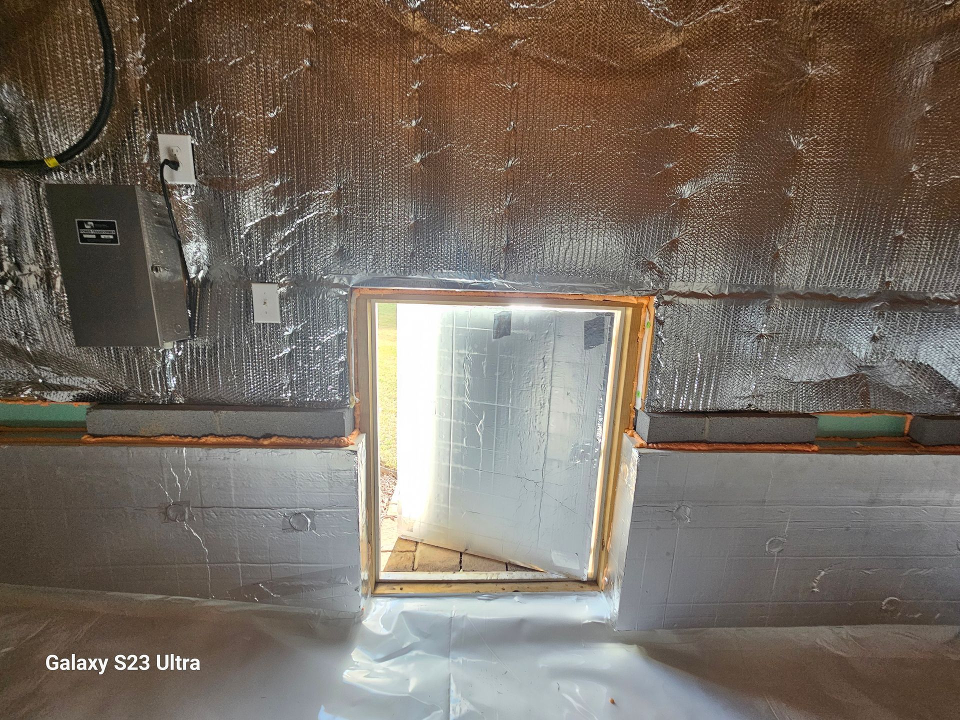 Interior view of a room with exposed insulation and a rectangular opening, possibly a door or window frame.