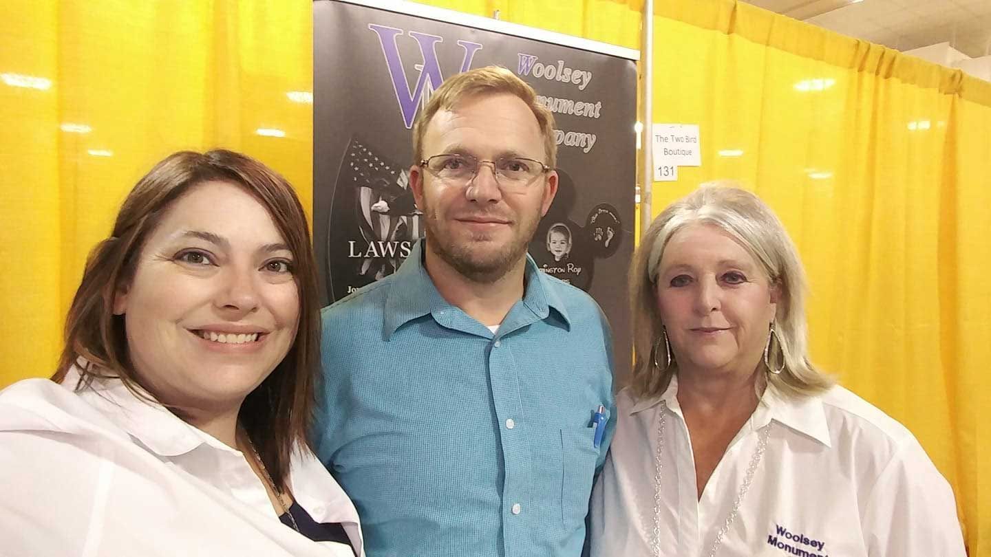 A man and two women are posing for a picture in front of a yellow curtain.