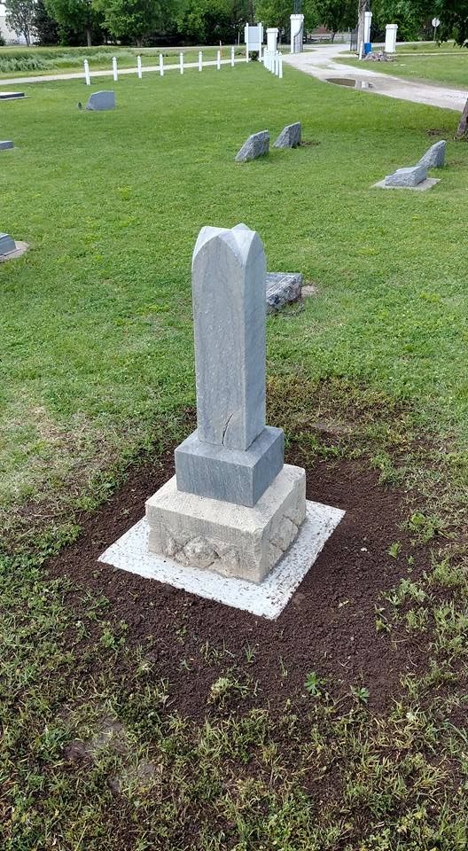 A gravestone is sitting in the middle of a cemetery.
