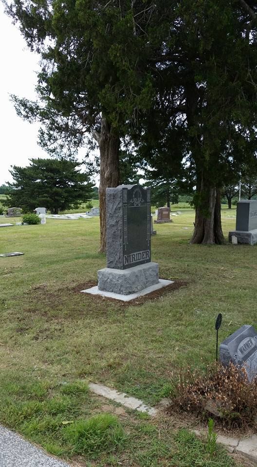 A gravestone in a cemetery with trees in the background.