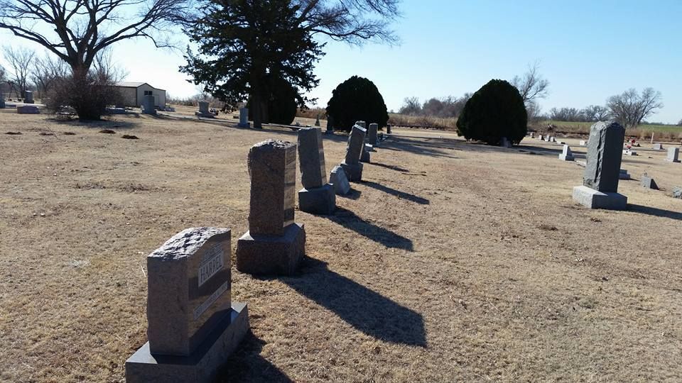 A row of graves in a cemetery with trees in the background