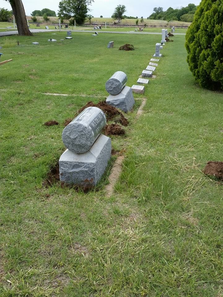 A cemetery with a row of graves sitting in the grass.