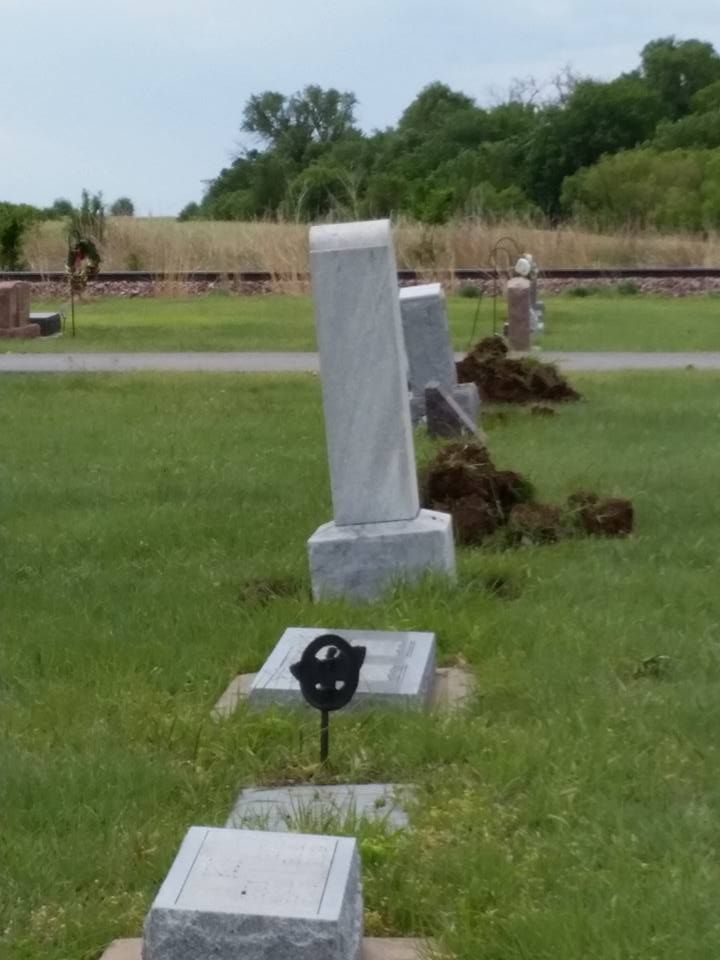 A row of graves in a cemetery with trees in the background