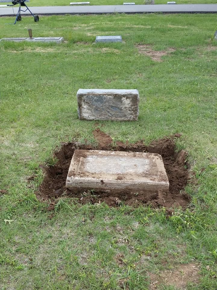 A grave in a cemetery with a concrete slab in the middle of it.