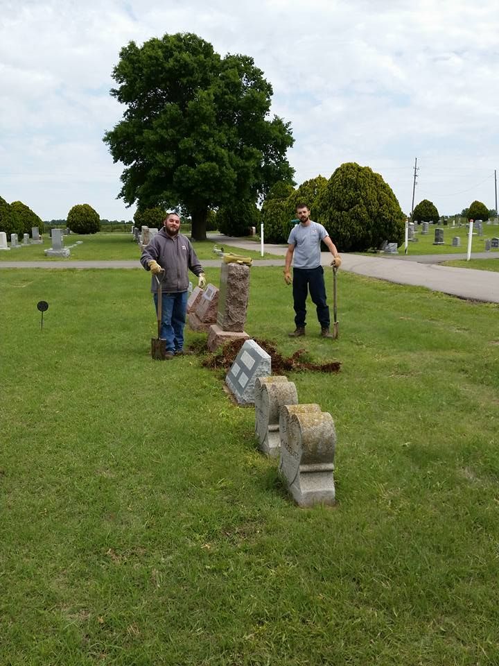 Two men are digging in a cemetery with shovels.