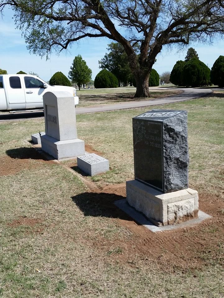 Two graves in a cemetery with a truck parked in the background