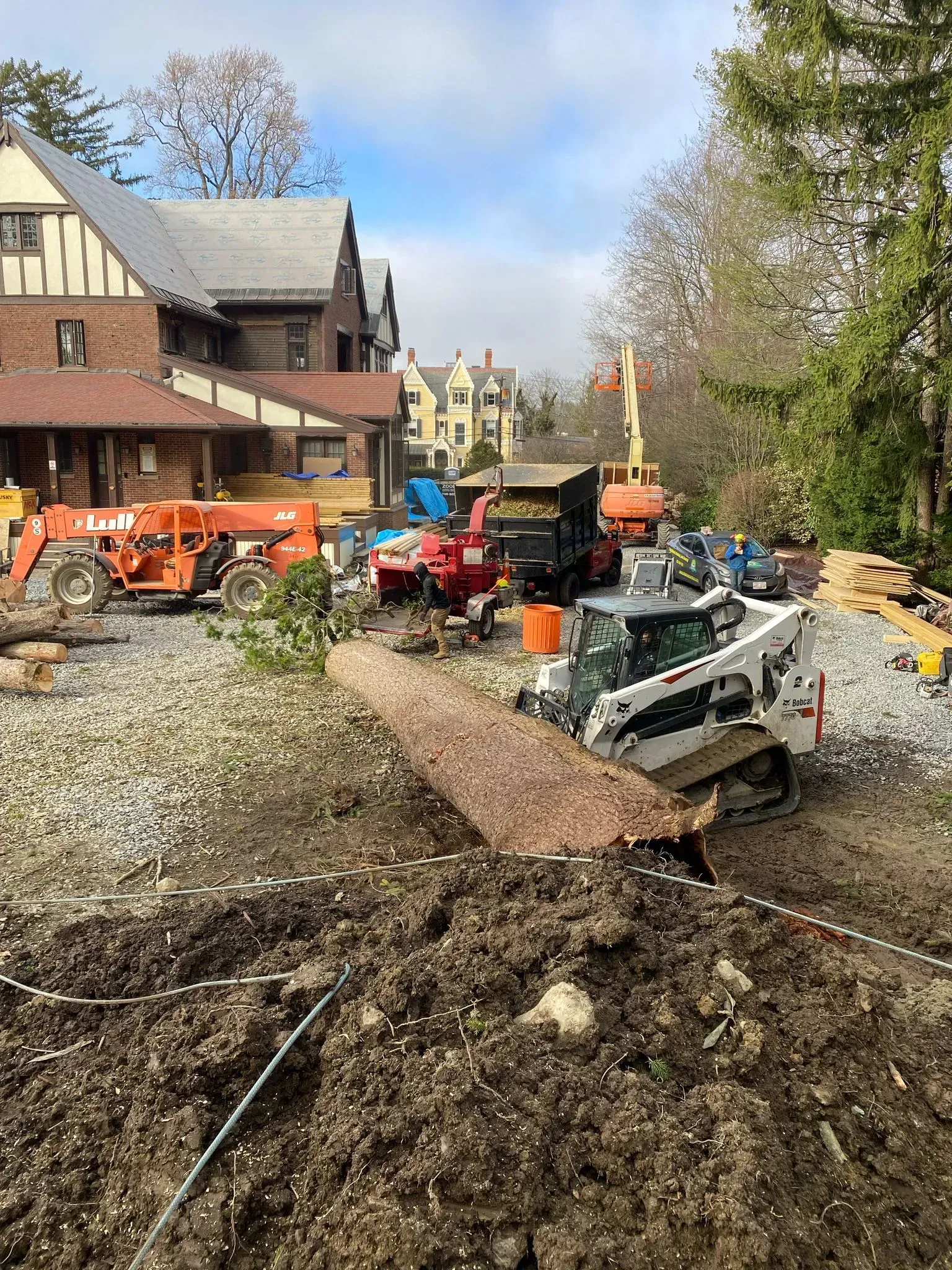 Construction vehicles and workers clearing debris in a residential street after a landslide.