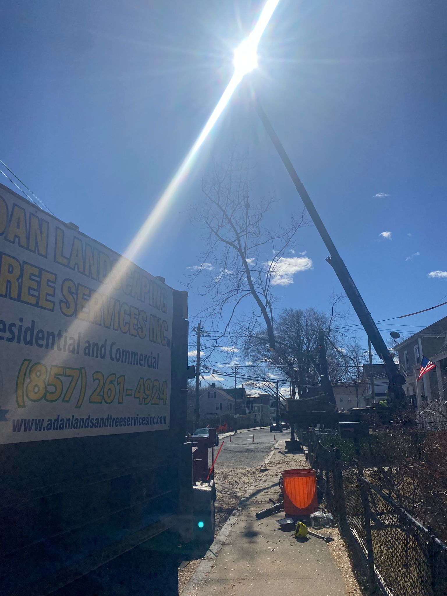 Bright sunny outdoor scene with a crane, construction sign, and a fenced yard with a red bucket.