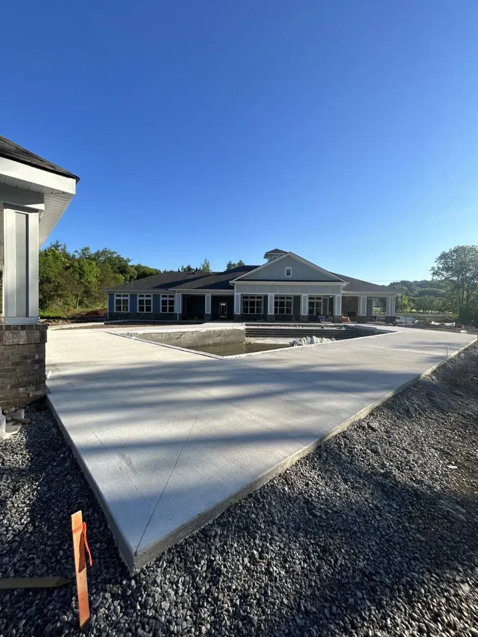 New concrete driveway and building construction under a blue sky.