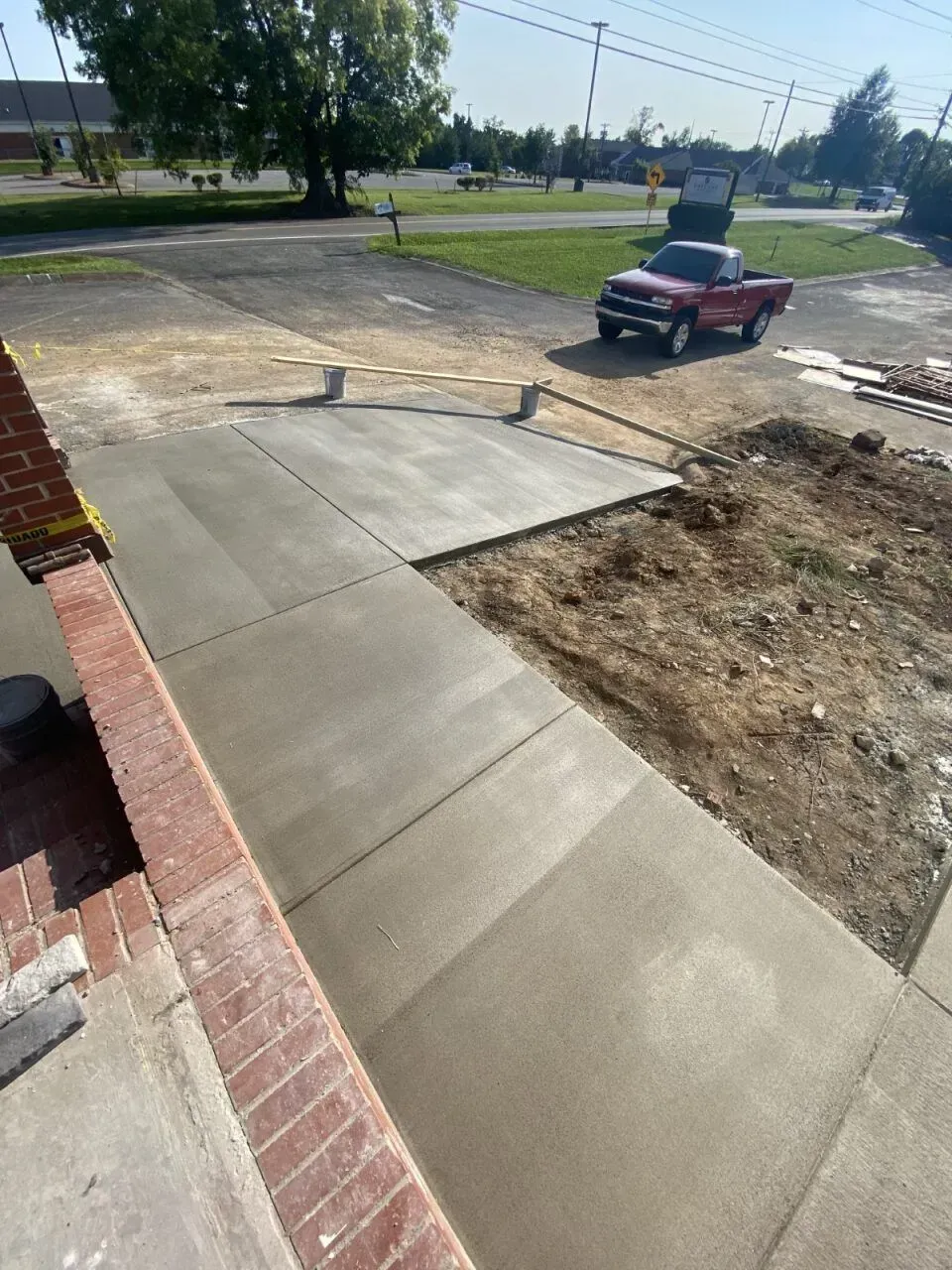 Newly poured concrete walkway with red truck in background.
