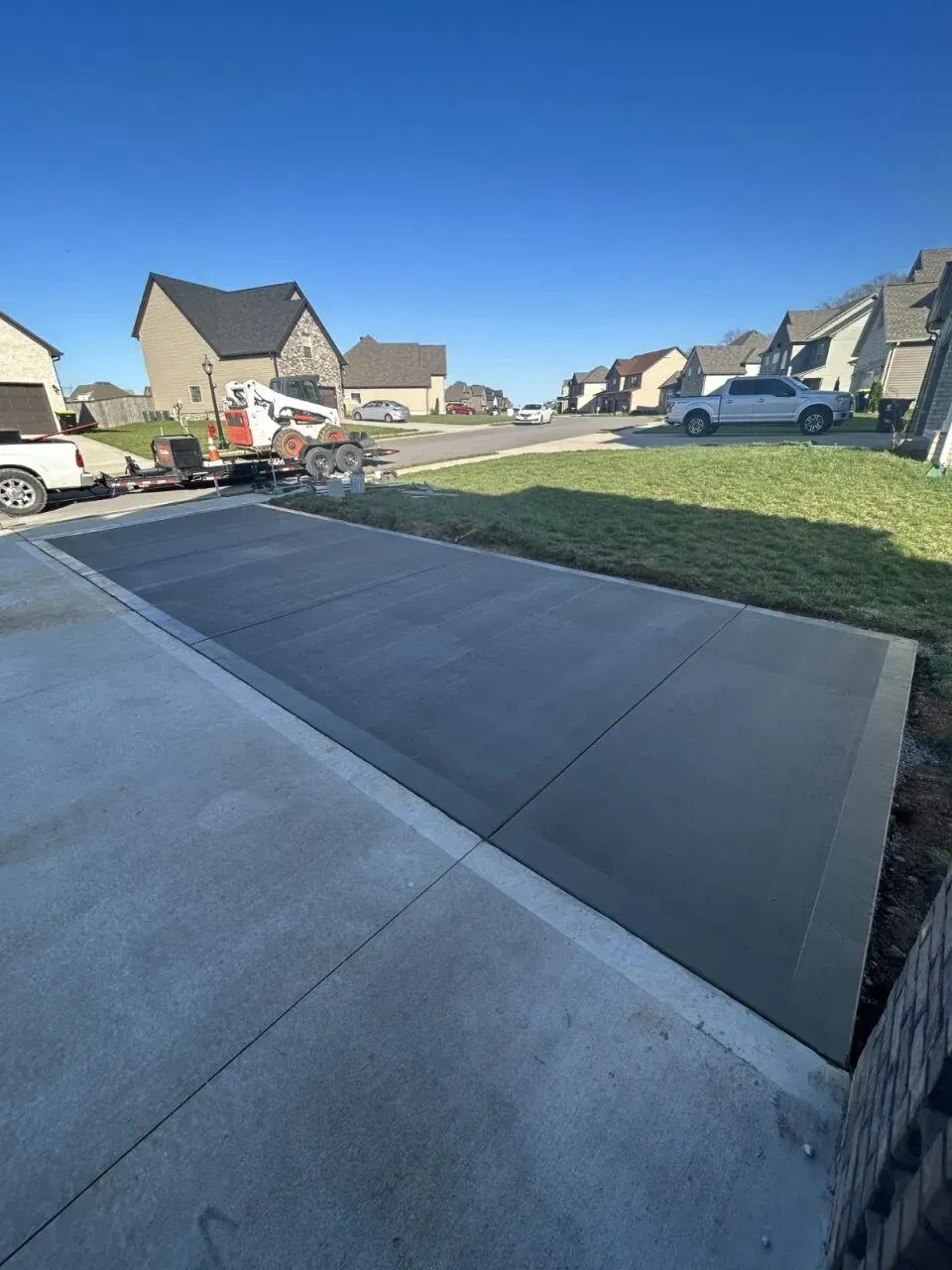 Newly poured concrete driveway extension in a suburban neighborhood.