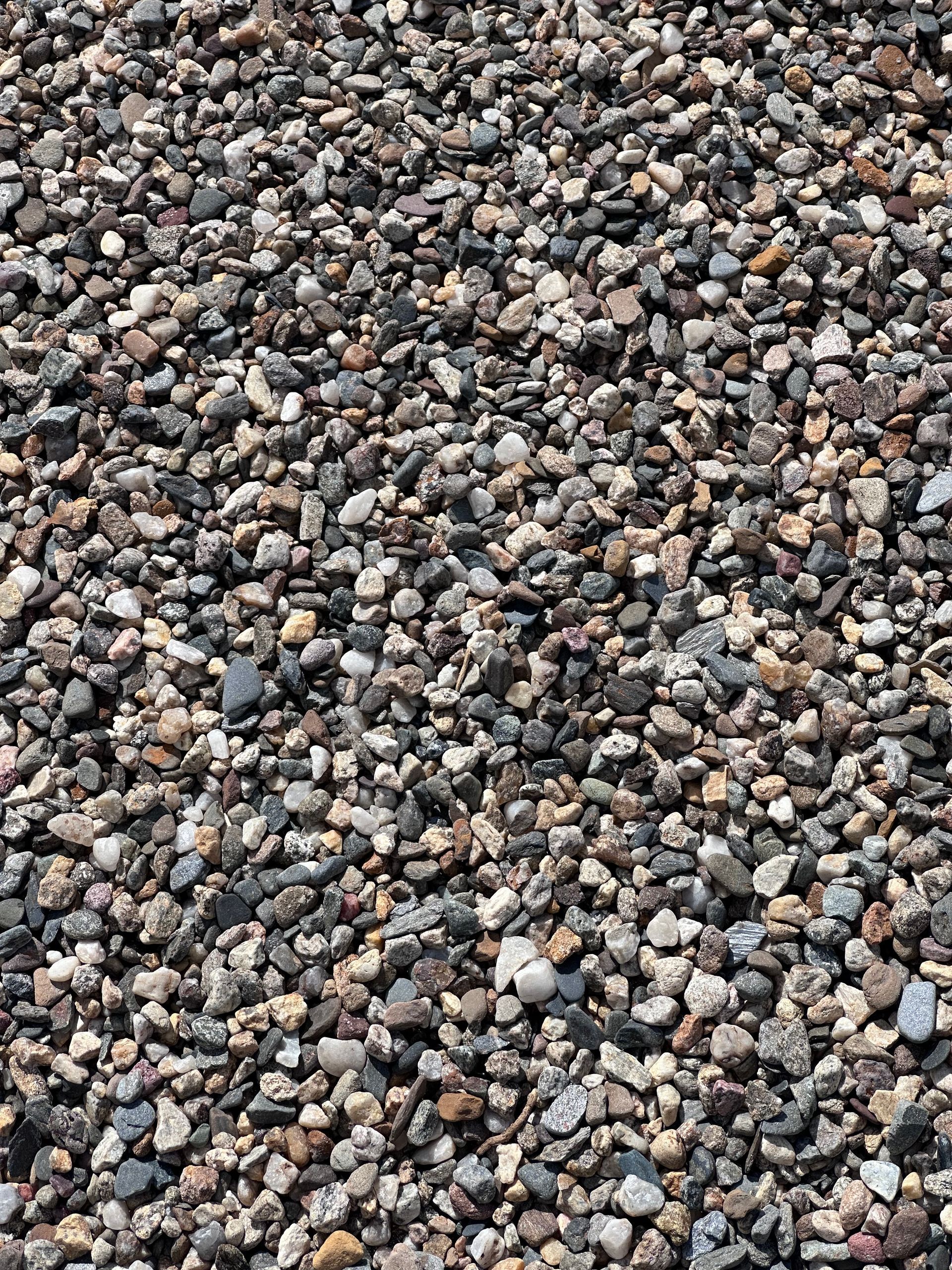 A pile of gravel is sitting on top of a grass covered field.