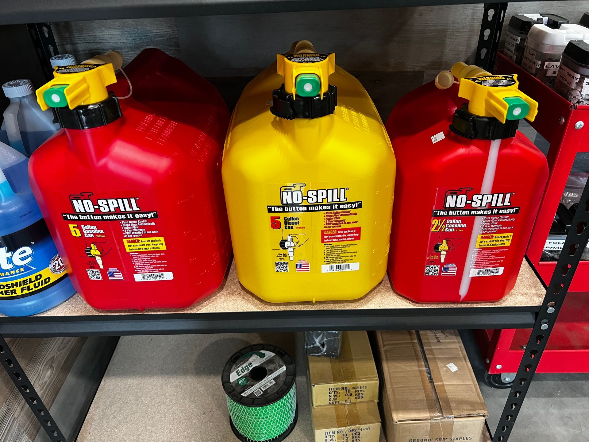 Three red and yellow gas cans are on a shelf.
