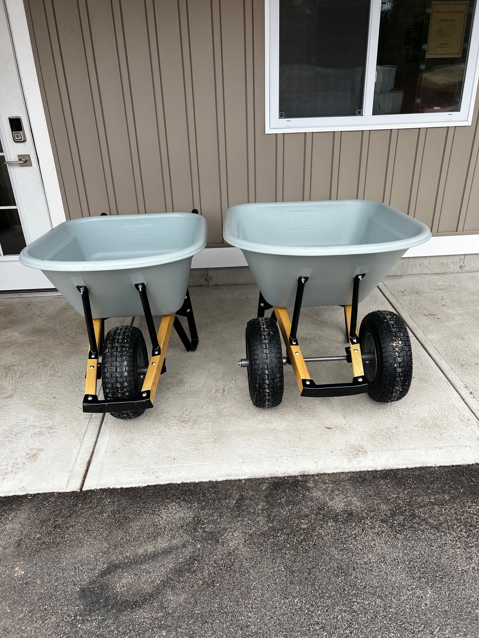 Two wheelbarrows are sitting on a sidewalk in front of a building.