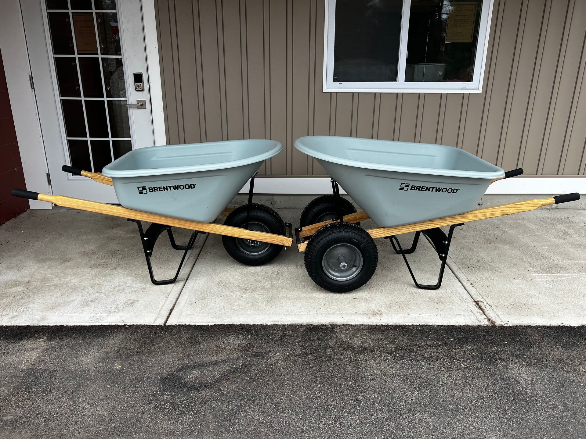Two wheelbarrows are parked on the sidewalk in front of a building.
