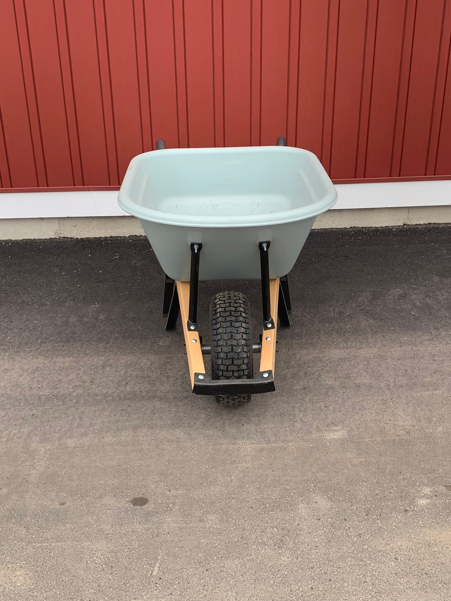 A wheelbarrow is sitting on the ground in front of a red building.