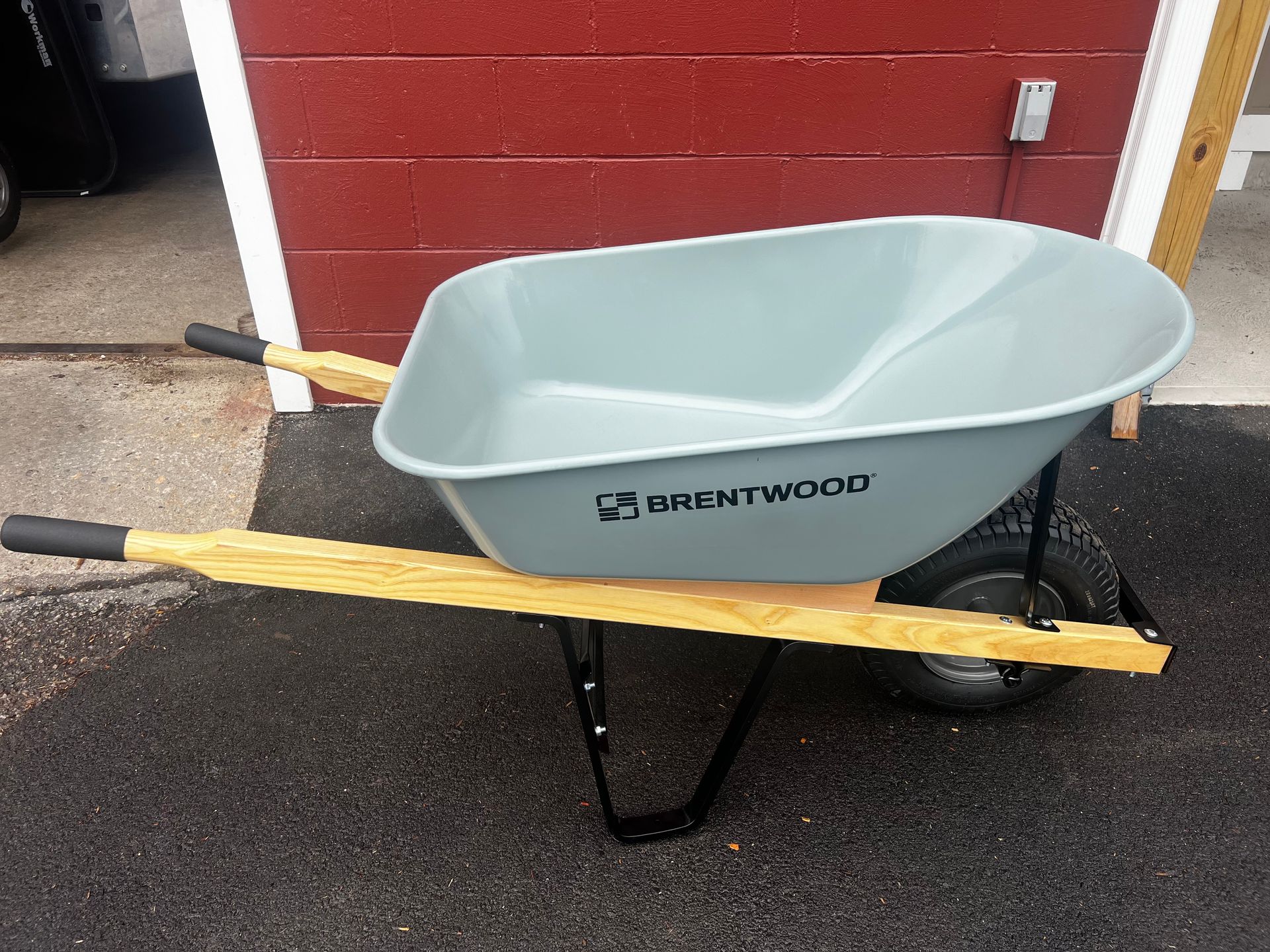A wheelbarrow is sitting in front of a red brick building