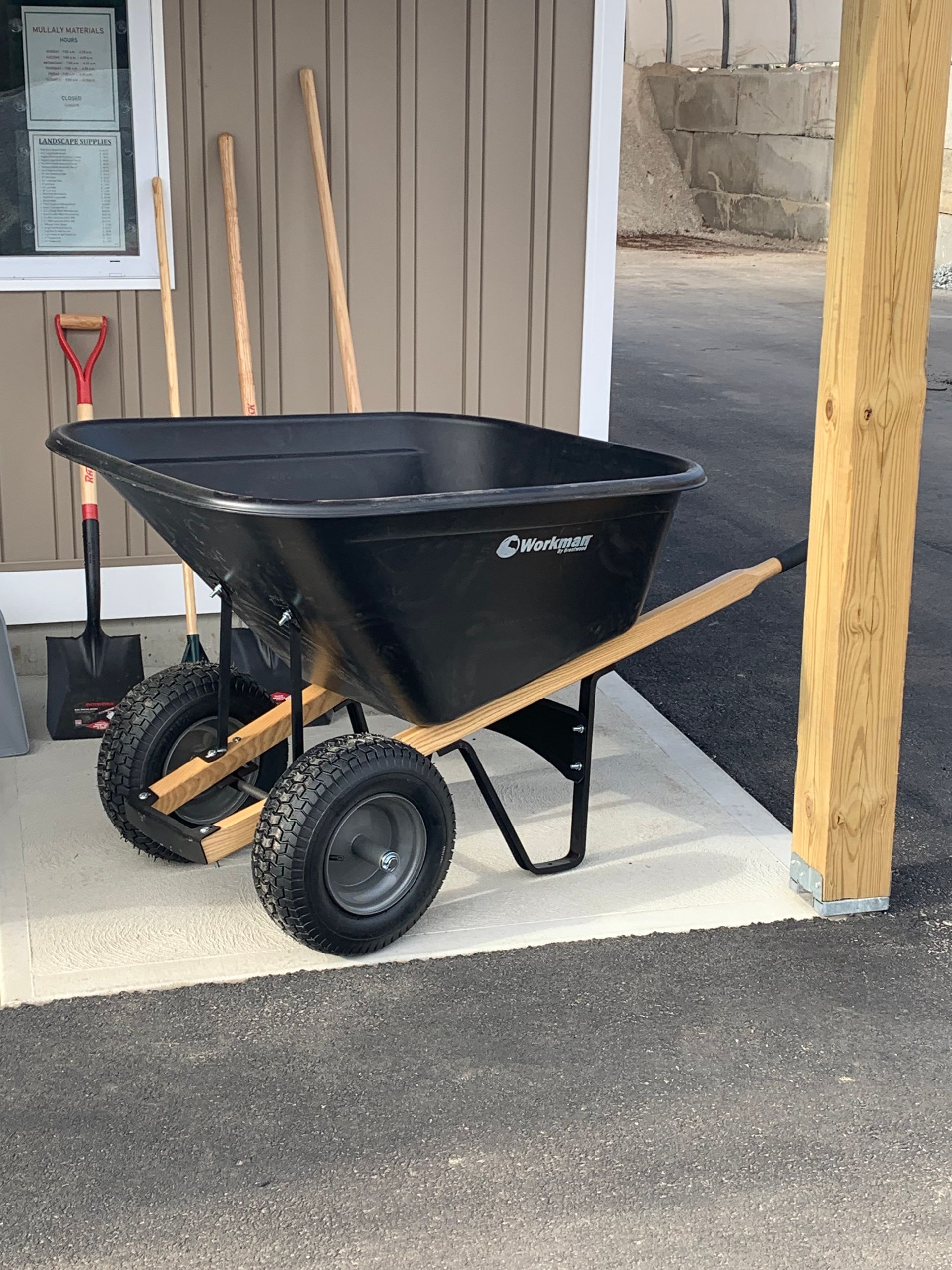 A black wheelbarrow is parked in front of a building.