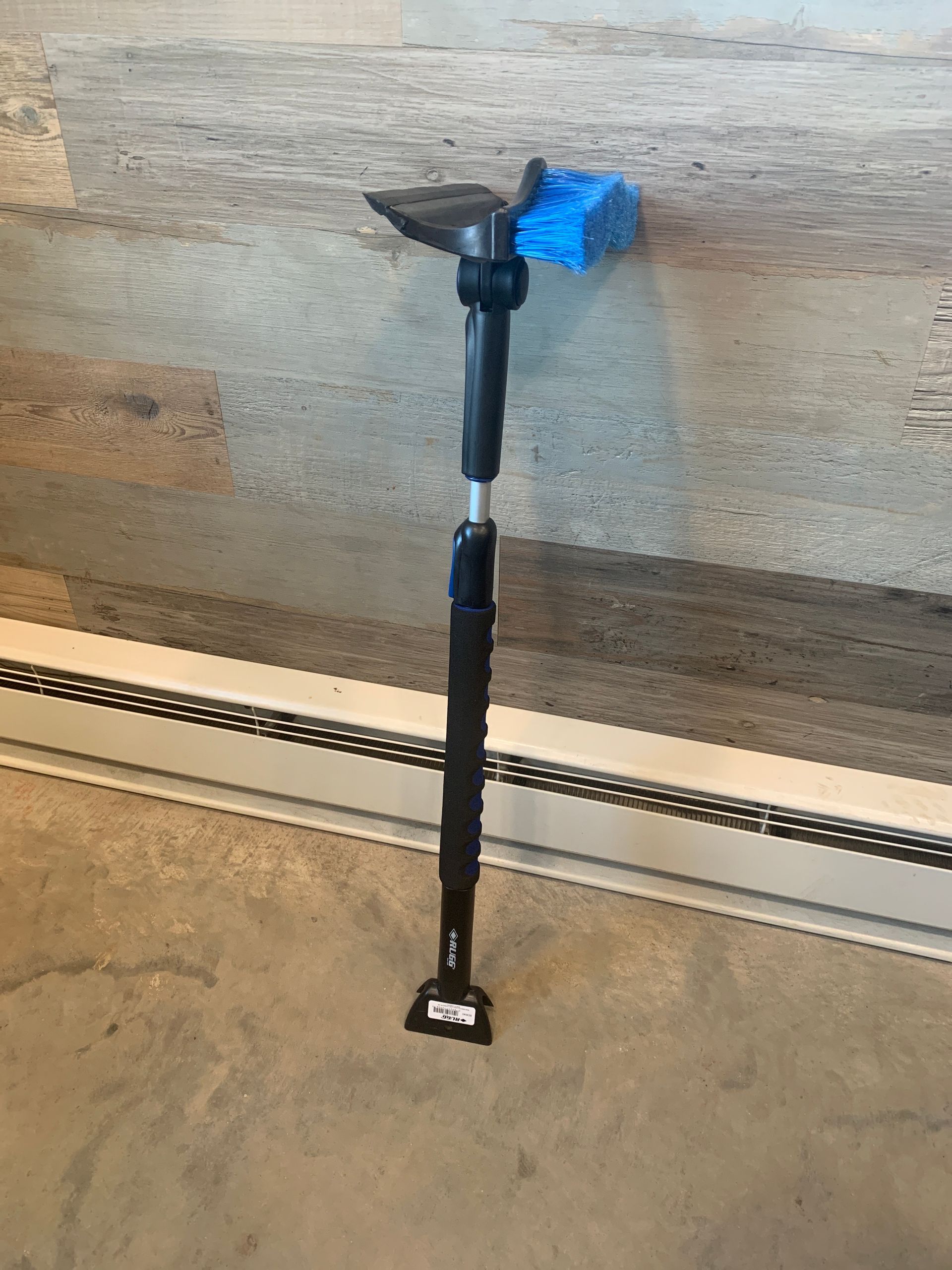 A black pole with a blue object attached to it is sitting on a concrete floor.