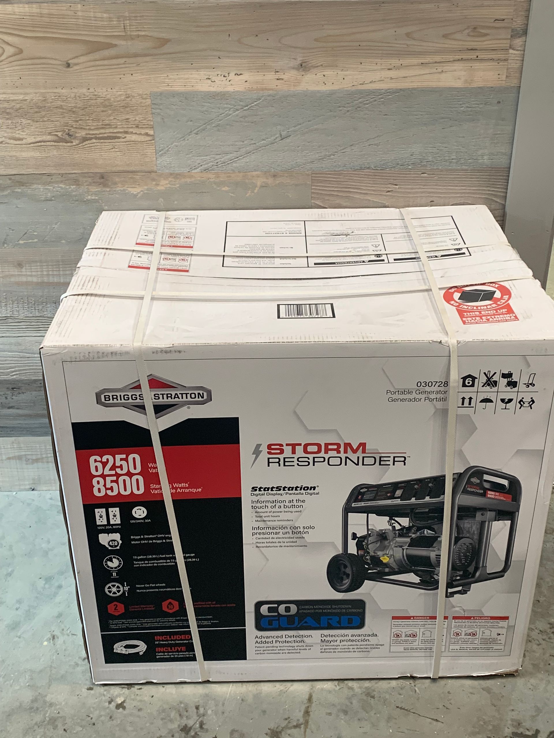 A box of a generator is sitting on a wooden floor.
