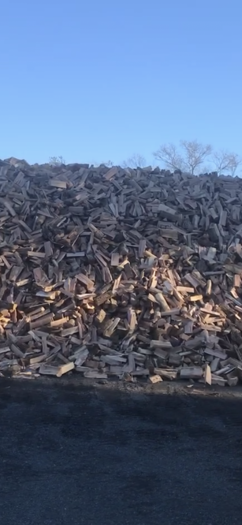 A large pile of wood is sitting on top of a hill.