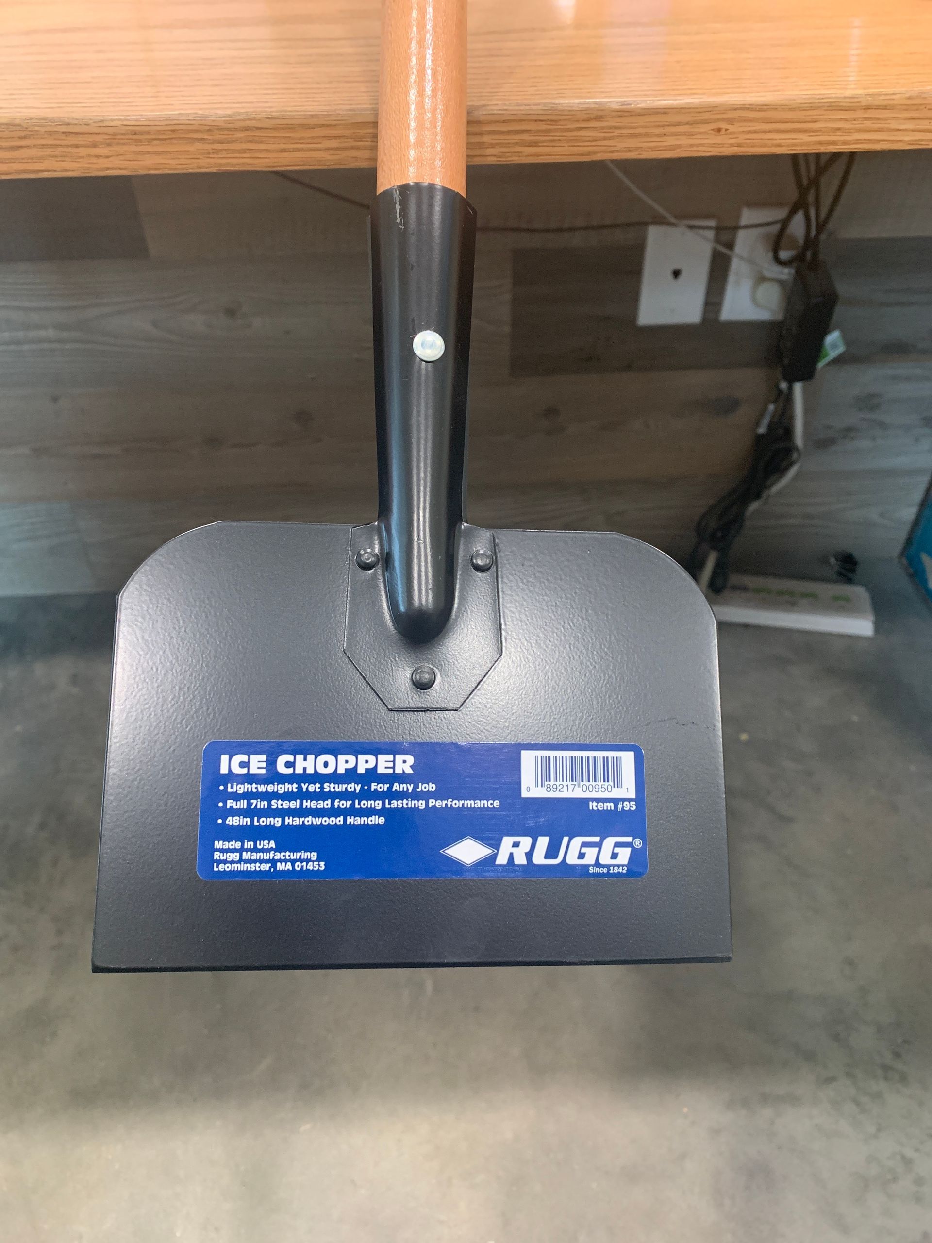 A shovel with a wooden handle is sitting on top of a wooden table.