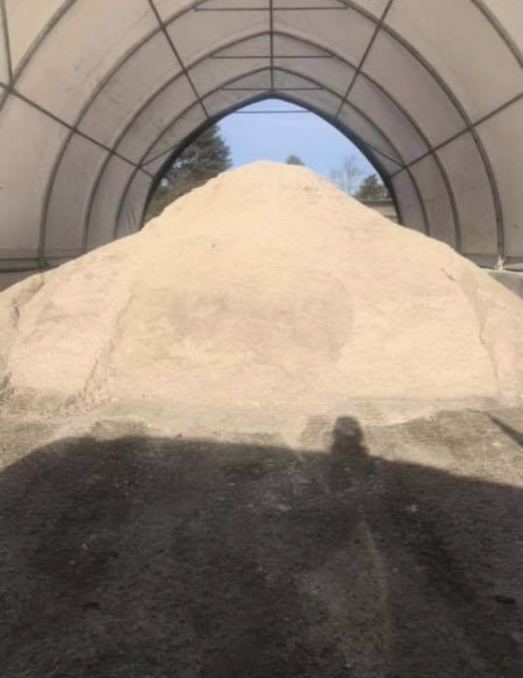 A large pile of sand is sitting inside of a tent.