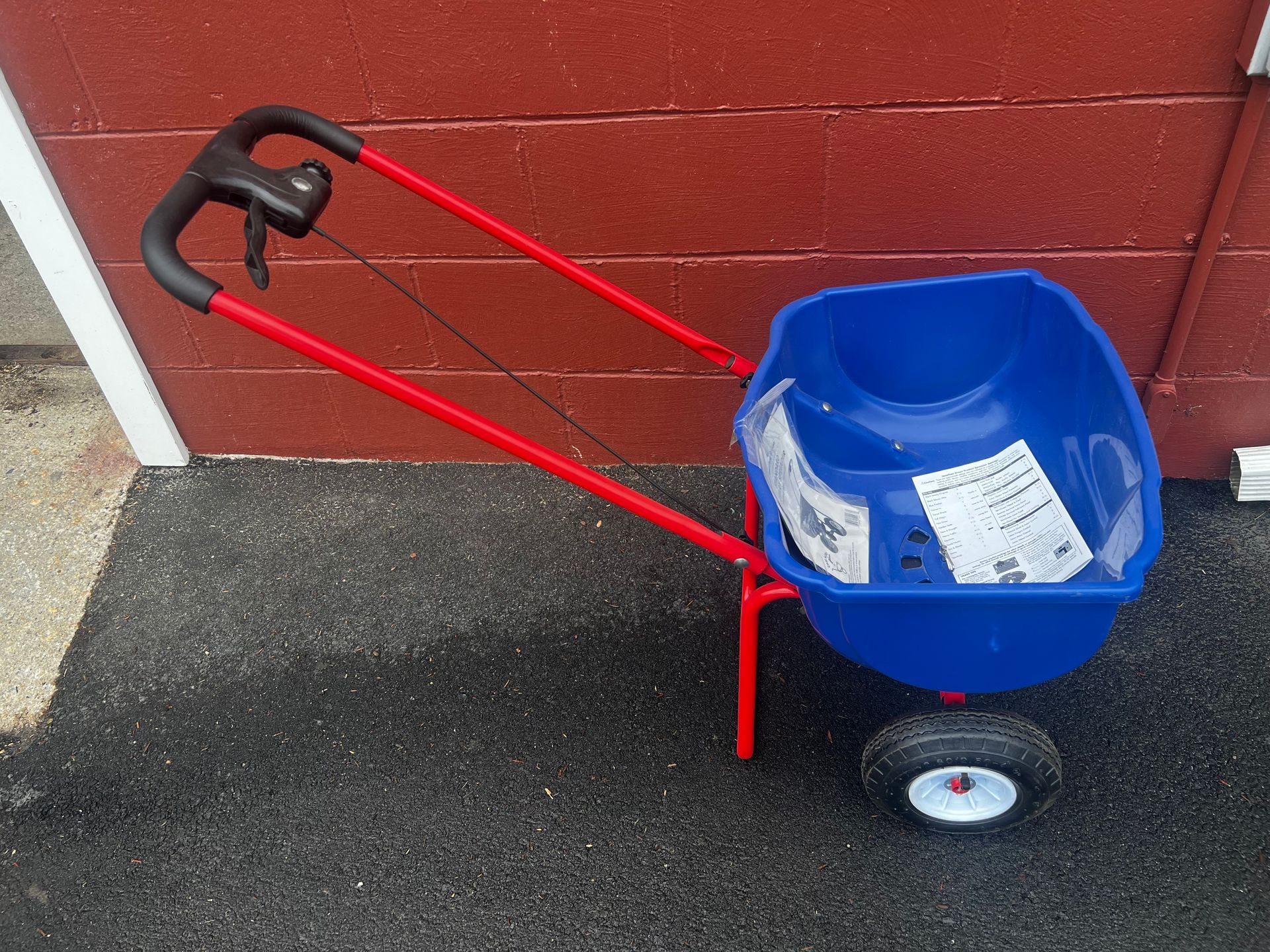 A blue wheelbarrow with a red handle is sitting on the ground
