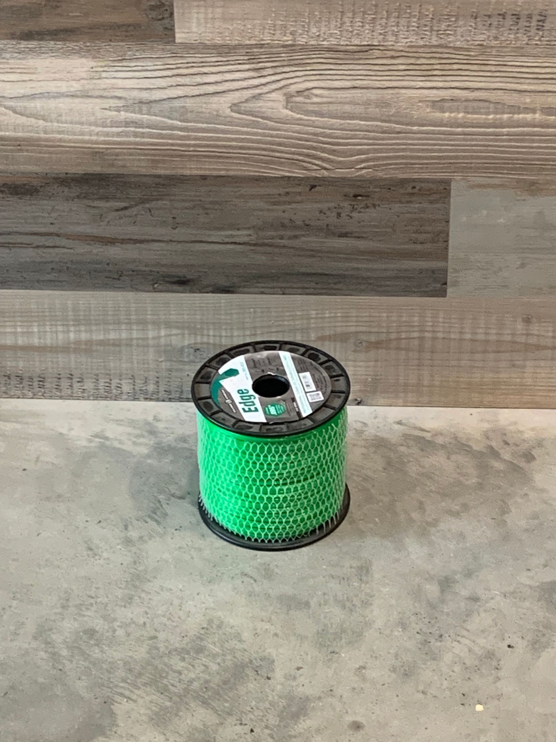 A spool of green string is sitting on a wooden table.