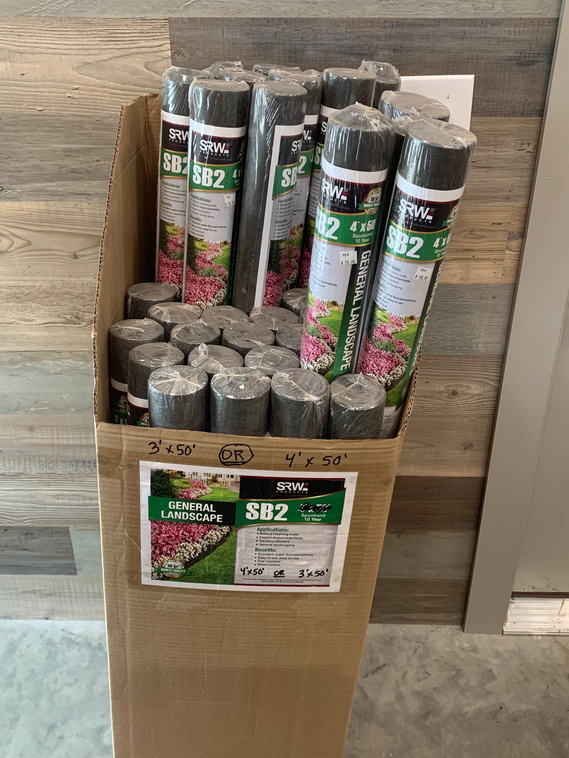 A cardboard box filled with rolls of weed barrier.