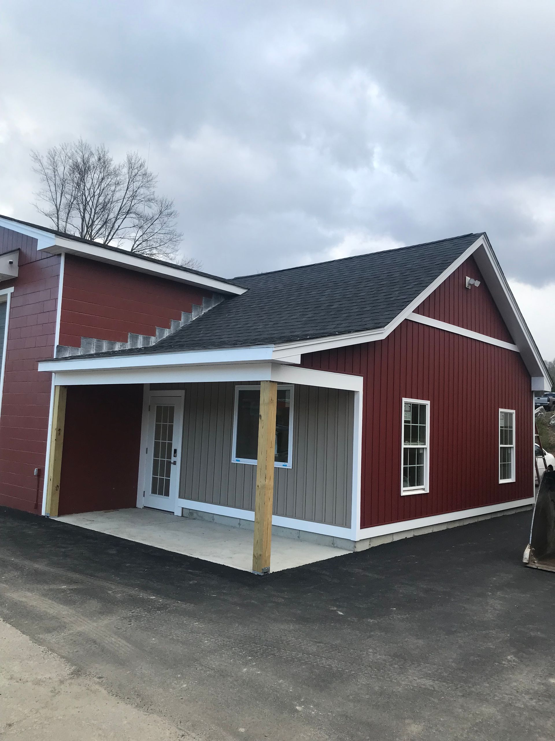 A red house with a black roof and a porch